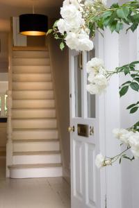 a hallway with a white door and stairs with white flowers at Stylish, Spacious, Oxford Townhouse, Driveway parking in Oxford