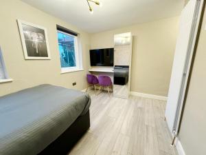 a bedroom with a bed and a desk and a tv at Stylish Studio minutes away from Wembley in London
