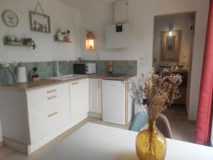 a kitchen with a table and a vase with flowers in it at Le ty cocon in Saint-Frégant