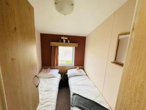 twee bedden in een kleine kamer met een raam bij 3 Bedroom 2 Bathroom Caravan Charlie Delta in Saint Osyth +3 foto's