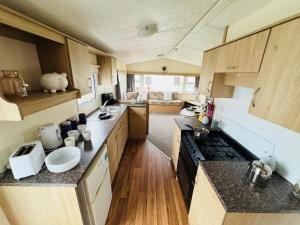 een keuken met houten kasten en een spoelbak erin bij 3 Bedroom 2 Bathroom Caravan Charlie Delta in Saint Osyth