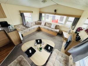 een woonkamer met een bank en een tafel bij 3 Bedroom 2 Bathroom Caravan Charlie Delta in Saint Osyth