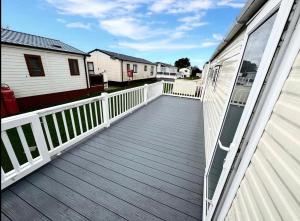 een houten terras op een huis met een balkon bij 3 Bedroom 2 Bathroom Caravan Charlie Delta in Saint Osyth