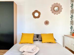 ein Bett mit gelben Kissen und zwei Handtüchern darauf in der Unterkunft Baux'M Chic - Alpilles, Grand Studio Cosy, Clim, 4 personnes in Les Baux-de-Provence + 74 Fotos