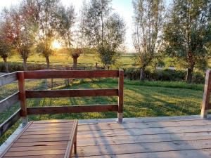 a bench sitting on a wooden boardwalk in a field at glamping met landelijk uitzicht in Spanga