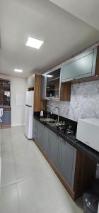 uma cozinha com pia e geladeira em Apartamento 3 quartos com suíte em Itapema