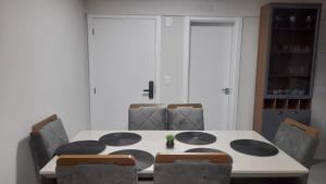 uma sala de jantar com uma mesa e cadeiras brancas em Apartamento 3 quartos com suíte em Itapema