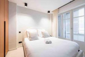 a bedroom with a large white bed with a window at La suite Versailles Croisette in Cannes