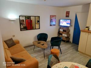 a living room with a couch and chairs and a tv at Studio au cœur de Quiberon in Quiberon