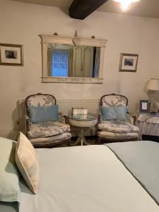 a bedroom with two chairs and a bed and a table at Yr Hen Felin - The Old Mill B&B in Morfa Nefyn
