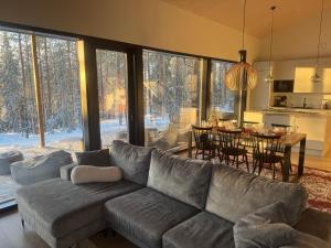 a living room with a gray couch and a dining room at Himos Villa Aurinkorinne in Jämsä