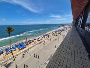 a beach with people and umbrellas and the ocean at Farol Barra Flat in Salvador