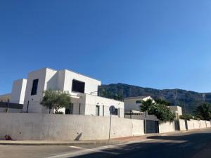 a white building on a street with mountains in the background at micasa in Denia