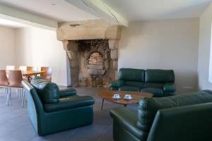 a living room with green leather furniture and a stone fireplace at Le Clos de l'Archeneau in Bressuire