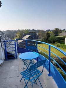 a blue table and two chairs on a balcony at Les Pins, plage à pied in Fouesnant