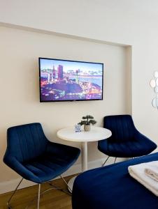 two blue chairs and a table with a tv on a wall at Апарт-отель в Панорама Бич in Batumi