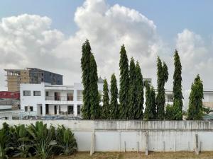 a row of trees in front of a white building at Jod & Naic Appartement in Abidjan