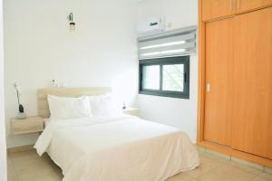 a bedroom with a white bed and a window at Jod & Naic Appartement in Abidjan