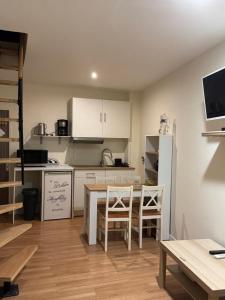 a kitchen with white cabinets and a table and chairs at Dépendance COLOMBES in Saint-Germain-en-Laye