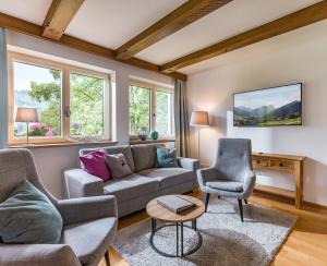 salon z kanapą, krzesłami i oknami w obiekcie Chalet Achenberg w mieście Brixen im Thale