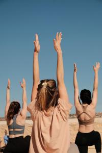 three women sitting on the beach with their hands in the air at La Vida Surf - Yoga Villa in Ounara