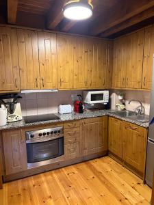 a kitchen with wooden cabinets and stainless steel appliances at Lo somni del riu in Llavorsí