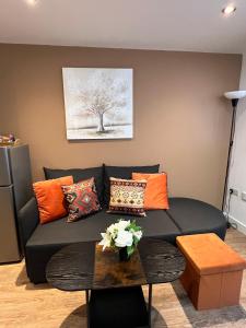 a living room with a black couch with orange pillows at Glastonbury Sacred Vault, Split-Level, 1 Bedroom in Glastonbury