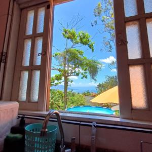 ein Küchenfenster mit Poolblick in der Unterkunft Chalé Completo Com Linda Vista para o Mar de Ilhabela in Ilhabela