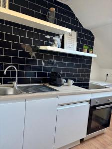 una cocina con fregadero y una pared de azulejos negros en Appartement vieille-ville de Boulogne, vue Cathédrale, en Boulogne-sur-Mer