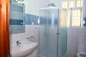 une salle de bain avec une douche en verre et un lavabo dans l'établissement Hôtel Maisons-Sifa, à Butare 78 autres photos