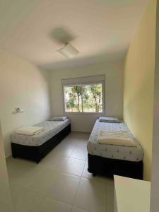 two beds in a room with a window at Casa Pé na Areia Boiçucanga in São Sebastião +11 photos