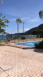 a swimming pool with lounge chairs next to the ocean at Casa Pé na Areia Boiçucanga in São Sebastião