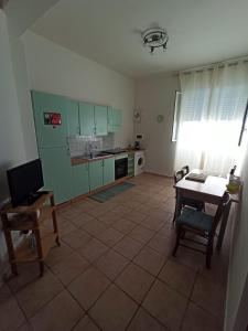 a kitchen with green cabinets and a table with a chair at Casa del Papavero in Piombino +2 photos