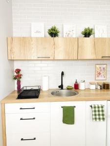 a kitchen with white cabinets and a sink at Apartamenty Prestige Harmony Rosiczkowa in Augustów +4 photos