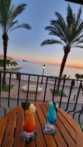 a wooden table with two cocktails on top of the beach at Apartamentos Playa Pequeña in Benidorm