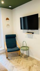 einen Stuhl, einen Tisch und einen TV an der Wand in der Unterkunft T2 neuf centre ville la tour du pin-Clim-parking-gare in La Tour-du-Pin