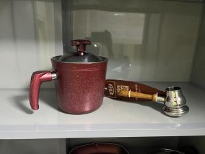 - une bouteille de vin dans une tasse rouge sur une étagère dans l'établissement comfort, à Madinaty