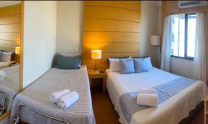 two beds in a hotel room with towels on them at Flat de Luxo Aeroporto Congonhas - Hotel in São Paulo