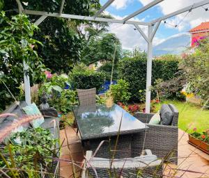 a patio with a table and chairs in a garden at Small Room - FLAMINGA'S PLACE in Lajes do Pico