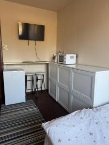ein Hotelzimmer mit Bett und einer Küche mit Mikrowelle in der Unterkunft 2#room in Jarocin