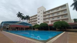 ein Hotel mit einem Schwimmbad vor einem Gebäude in der Unterkunft KP Hotel Udonthani in Amphoe Kumphawapi