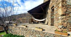 a stone building with a hammock outside of it at Cal Brugués - Casa de montanya in Ribes de Freser
