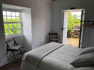 a bedroom with a bed and a window and a chair at Casa 3 Picos 1 in São Roque do Pico +41 photos