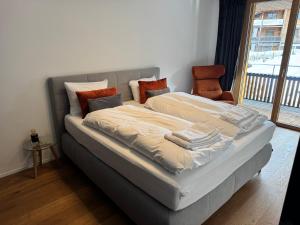 a large bed with pillows on it in a room at Beautiful Sunny New 1 Bed Apt (2.5Zim). Ski in/out in Flims +23 photos