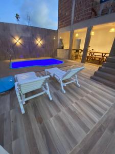una terraza con 2 bancos y una piscina en Recando Dourado Suíte 4, en São Miguel dos Milagres