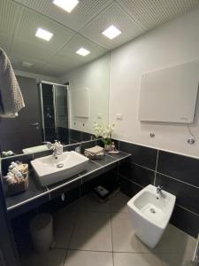 Un baño con dos lavabos, un inodoro y un espejo. en Il borghetto tranquillo, en Albano Laziale