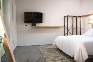 Un dormitorio con una cama y un televisor en la pared. en Urban Oasis Suite, en Ermoupoli