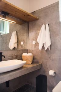 Un baño con lavabo y toallas en la pared. en Urban Oasis Suite, en Ermoupoli