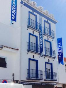 un edificio blanco con ventanas azules y balcones. en Hostal Acemar, en Marbella
