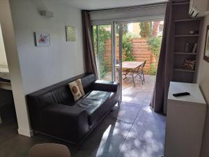 ein Wohnzimmer mit einer Ledercouch und einem Tisch in der Unterkunft Hameau du Puech, rez-de-jardin avec parking et clim in Cap d'Agde + 14 Fotos